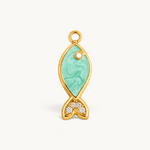 Nadare Co. gold-plated fish charm with teal enamel inlay and cubic zirconia tail detail on a white background.