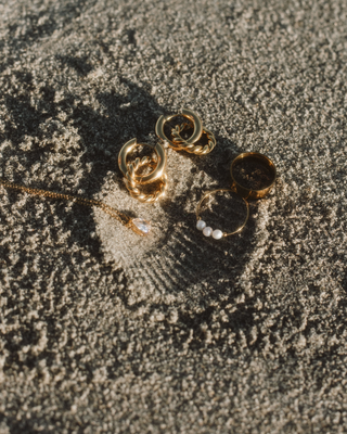 rings, earrings, and necklaces in sand