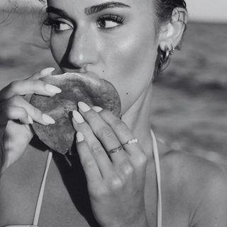 black and white image of a woman eating a mango