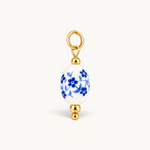 Nadare Co. oval porcelain charm with blue floral pattern and 14k gold plated stainless steel accents.