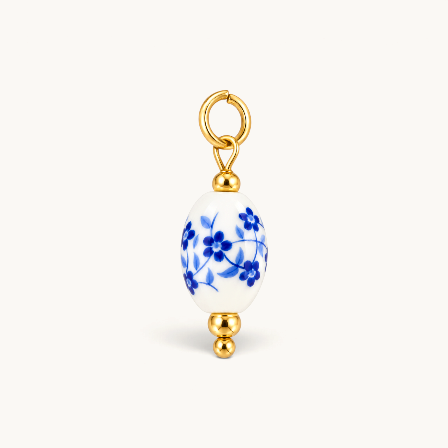 Nadare Co. oval porcelain charm with blue floral pattern and 14k gold plated stainless steel accents.