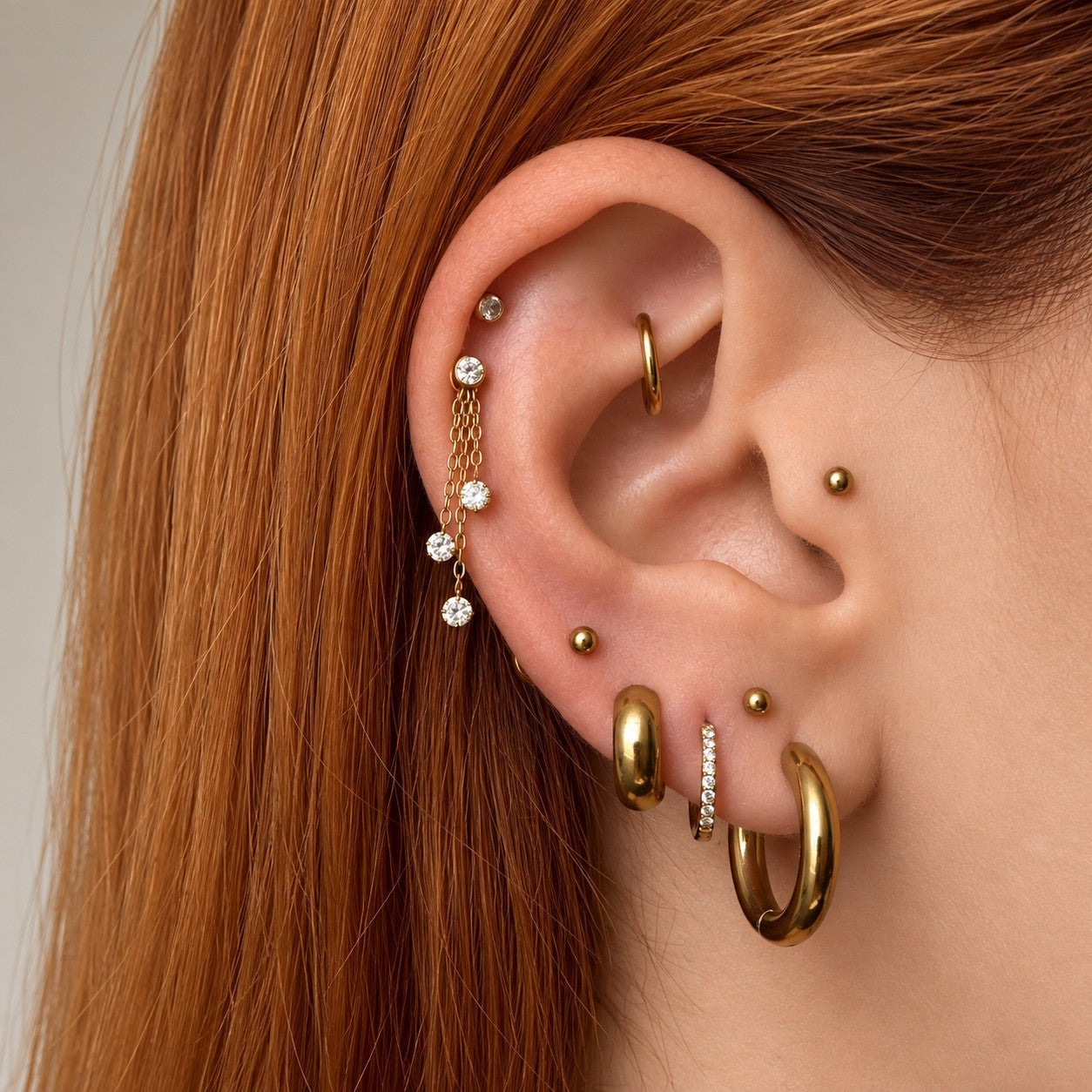 Nadare Co. Cascade Ear Charm featuring three delicate gold chains with sparkling crystals worn on a cartilage piercing.