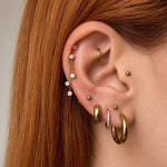 Nadare Co. Cascade Ear Charm featuring three delicate gold chains with sparkling crystals worn on a cartilage piercing.