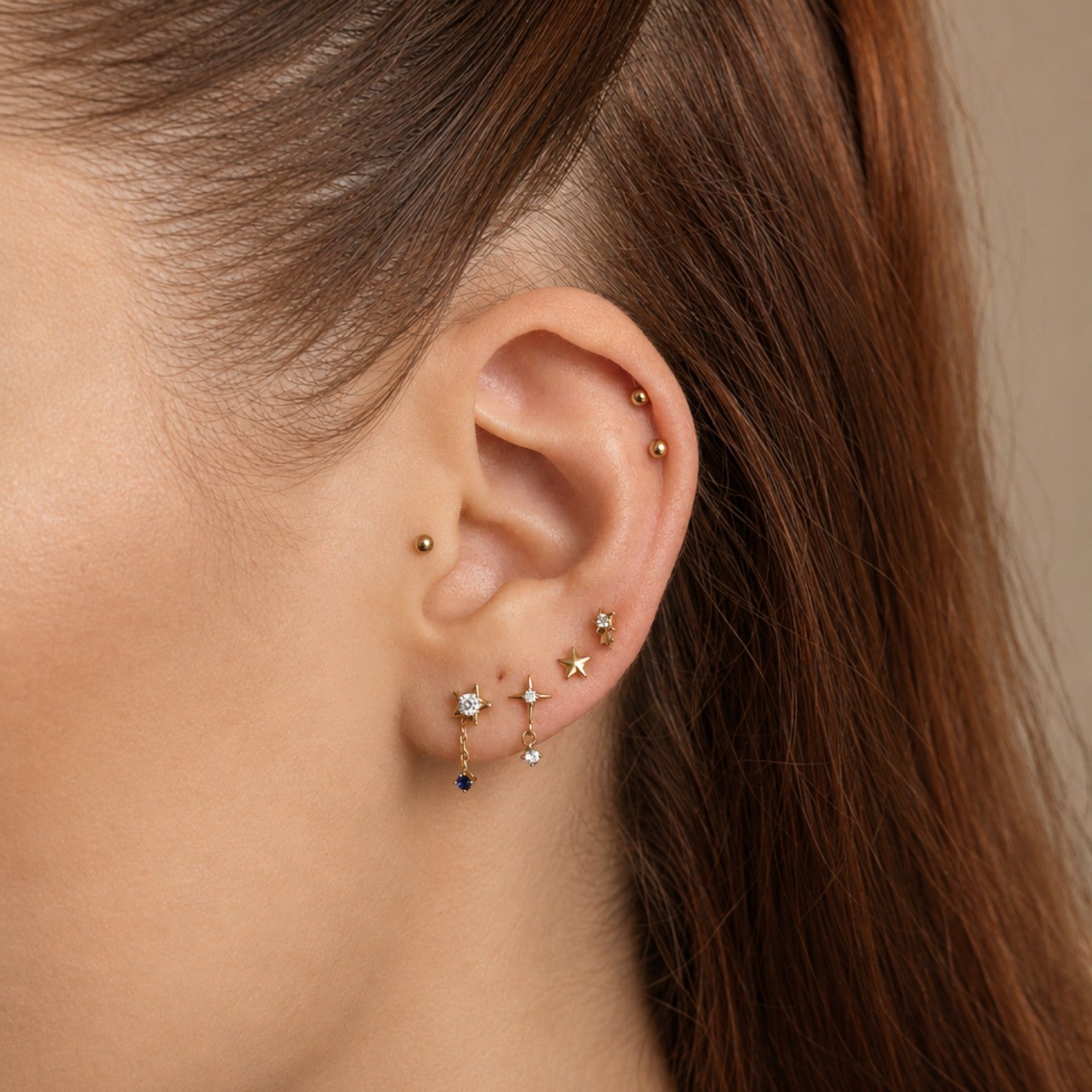 Nadare Co. Celeste gold star threadless earring front worn in a curated ear stack with multiple piercings.