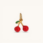 Nadare Co. Cherry Charm featuring glossy red enamel cherries with a green leaf on a gold-tone metal pendant.