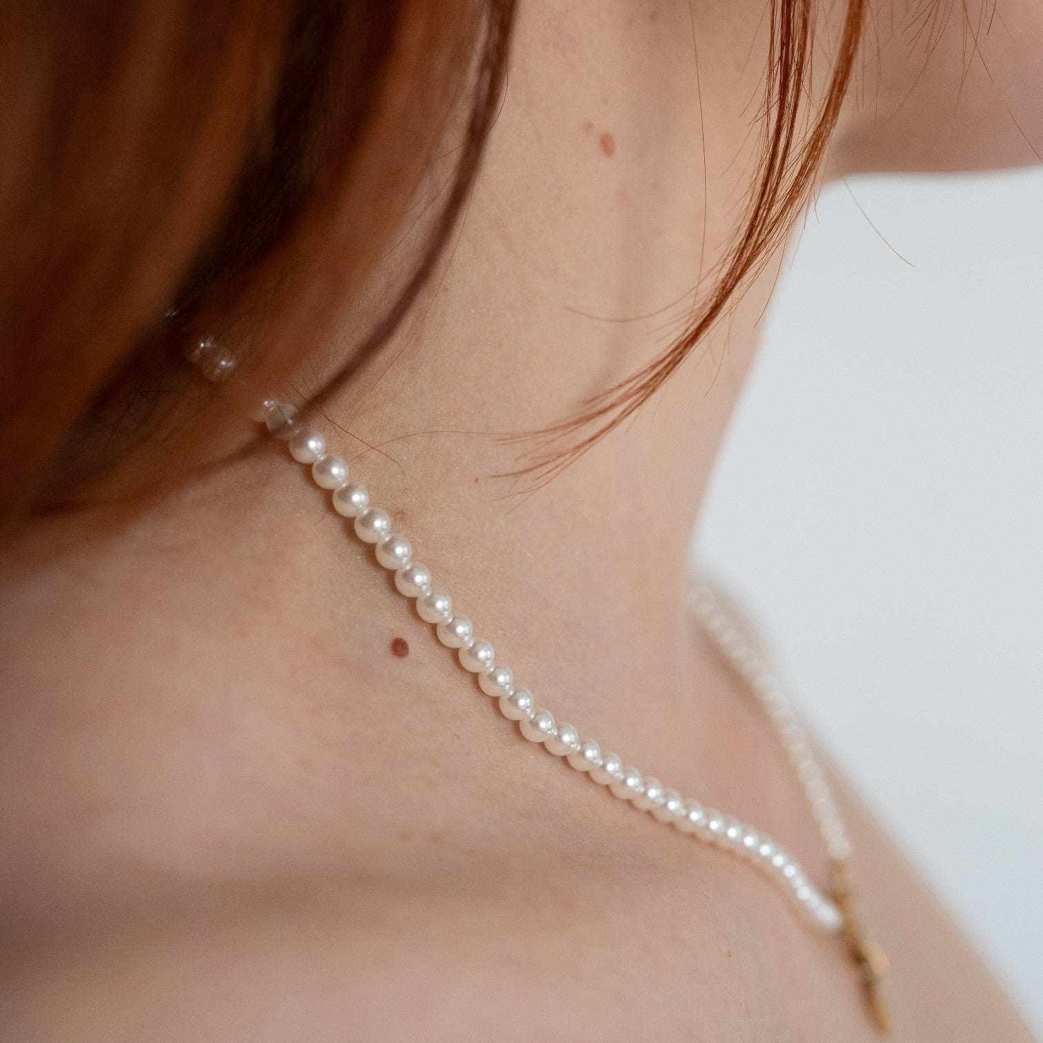 Nadare Co. Classic Pearl Chain featuring round white imitation pearls worn elegantly around a woman's neck.