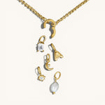 Nadare Co. customizable gold chain necklace with a clasp and various charms including a pearl, letter, and crystals.