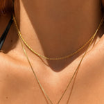 Nadare Co. Elena necklace featuring a delicate gold woven chain with a subtle shimmer worn layered on a model