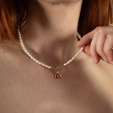 Nadare Co. freshwater pearl necklace with a gold clasp and red charm worn on a woman's neck