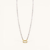 Nadare Co. freshwater pearl necklace with a gold-tone oval clasp charm connector on a cream background.