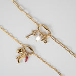 Nadare Co. gold carabiner clasp necklace featuring assorted charms including a key, pearl, and cowboy boot.