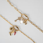 Nadare Co. gold carabiner clasp necklace featuring assorted charms including a key, pearl, and cowboy boot.
