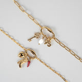 Nadare Co. gold carabiner clasp necklace featuring assorted charms including a key, pearl, and cowboy boot.