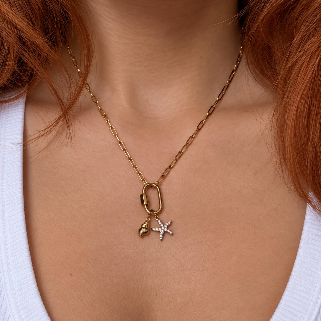 Nadare Co. gold conch shell and starfish charms on a link chain necklace worn on a person