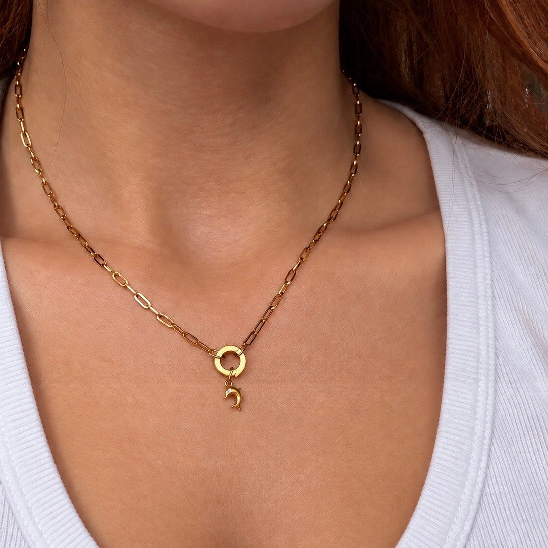 Nadare Co. gold dolphin charm necklace on a delicate chain worn around a woman's neck