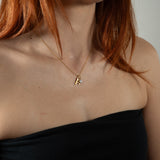Nadare Co. dainty gold initial A pendant necklace with a small sparkling birthstone charm worn on a woman