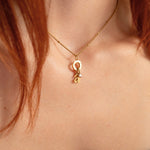 Nadare Co. gold initial necklace with a delicate mini birthstone charm worn on a person's neck