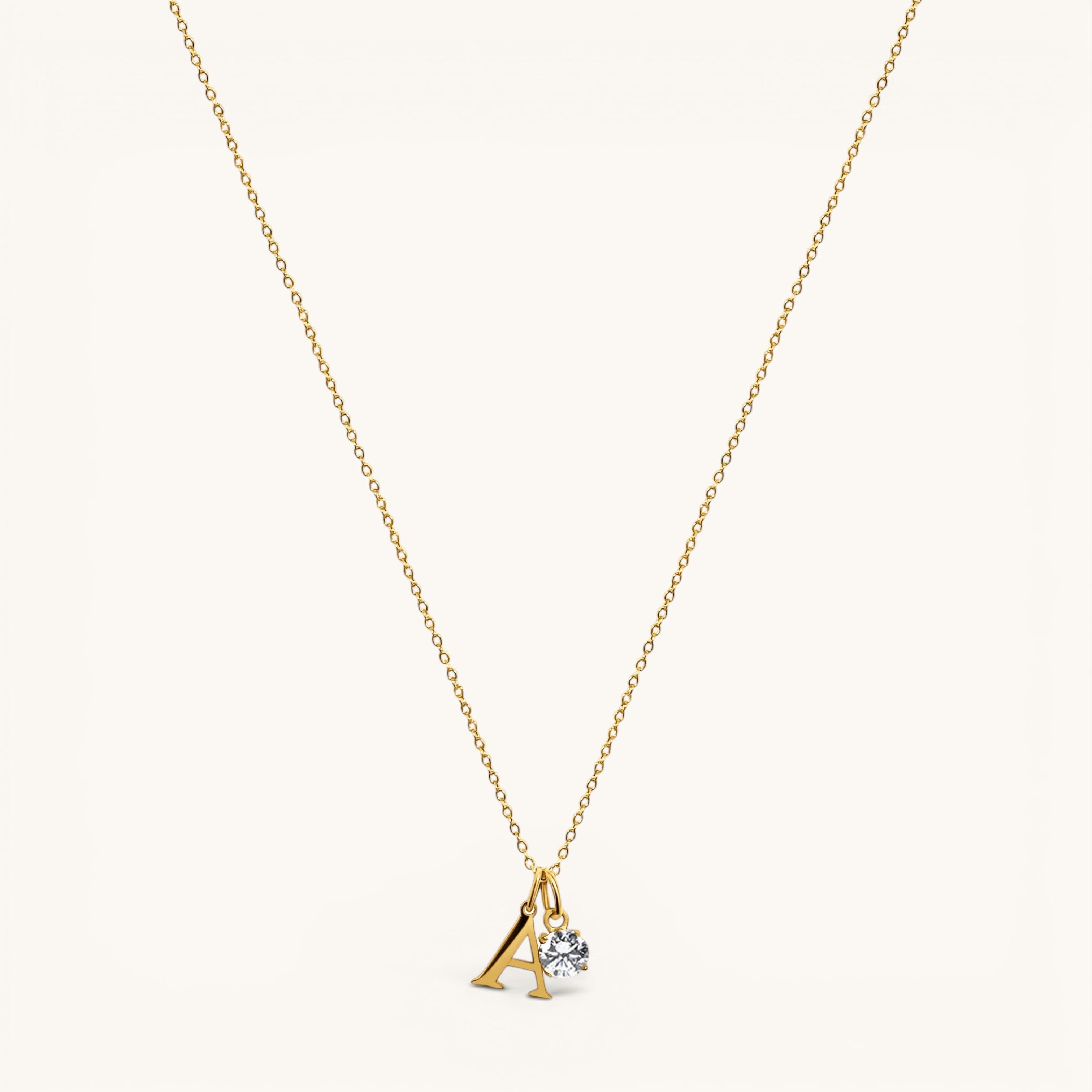 Nadare Co. dainty gold initial necklace with a letter A pendant and a sparkling round birthstone charm.