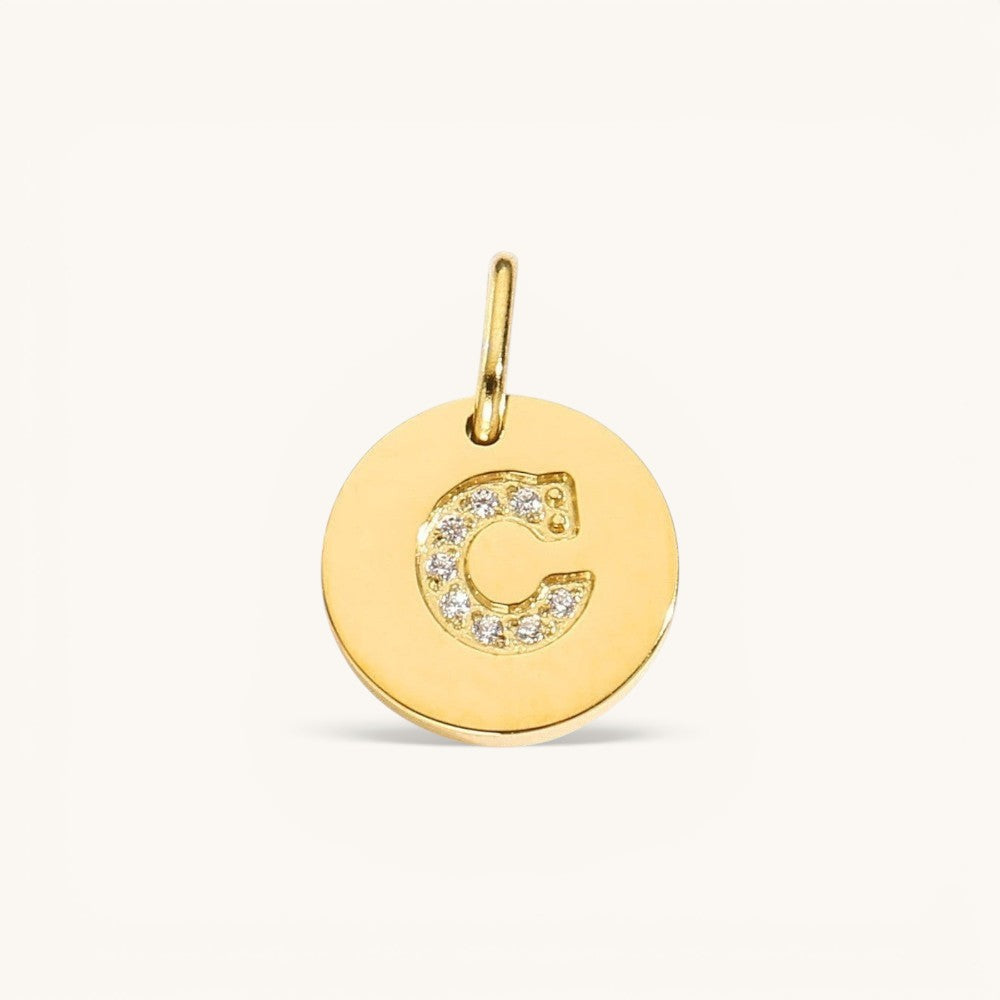 Nadare Co. gold initial charm with pavé set diamonds on a polished disc, letter C.