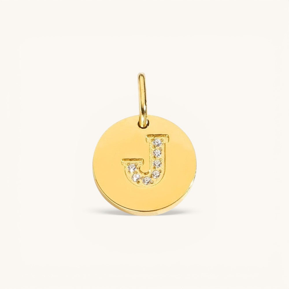 Nadare Co. gold initial charm with pavé set cubic zirconia on a polished disc.