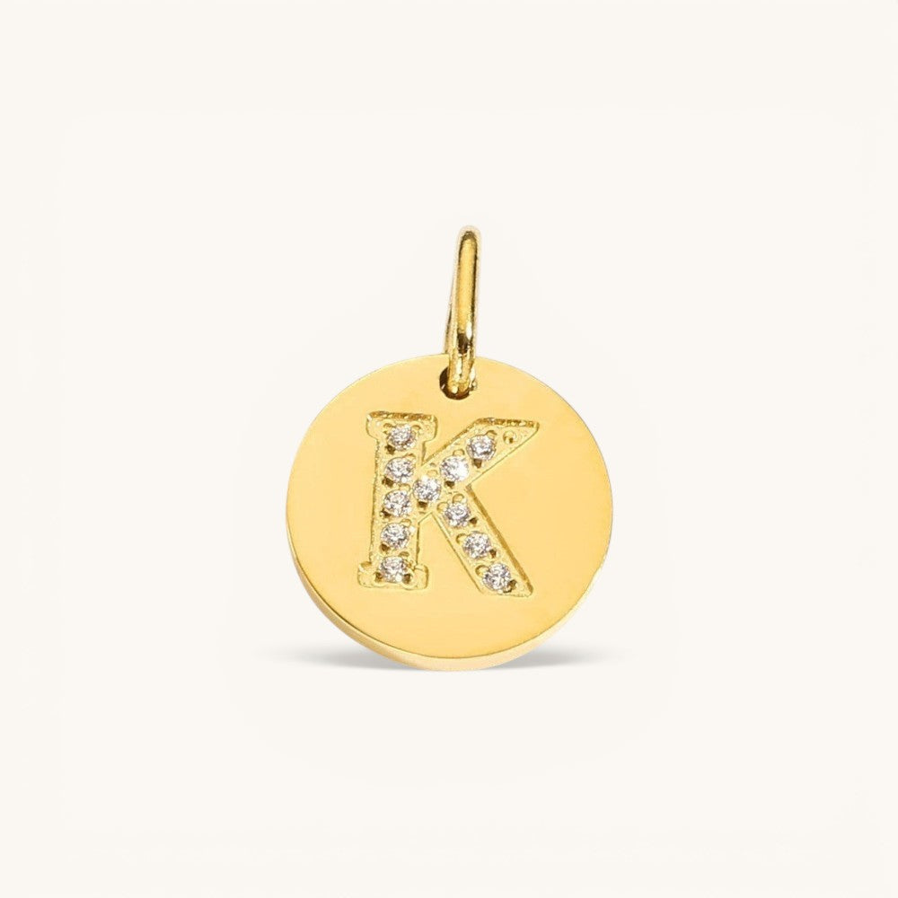Nadare Co. gold initial charm with pavé set crystals on a polished disc, letter K.