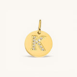 Nadare Co. gold initial charm with pavé set crystals on a polished disc, letter K.