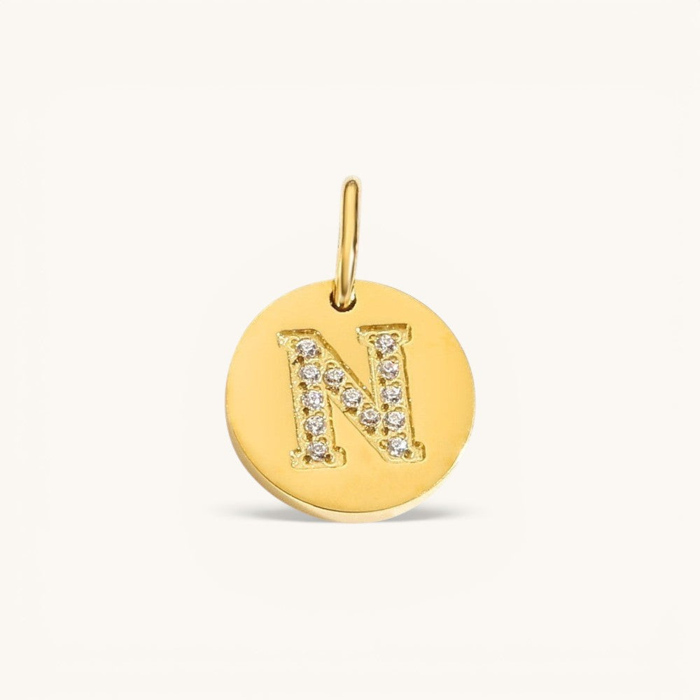Nadare Co. gold initial charm with pavé diamond letter N on a polished disc.