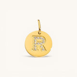 Nadare Co. gold initial charm with pavé crystal letter R on a polished disc.