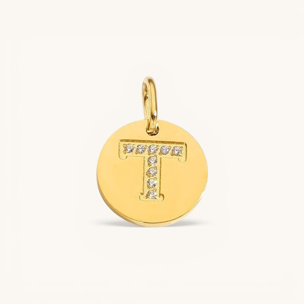 Nadare Co. gold initial charm with pavé set cubic zirconia stones forming the letter T on a polished disc.