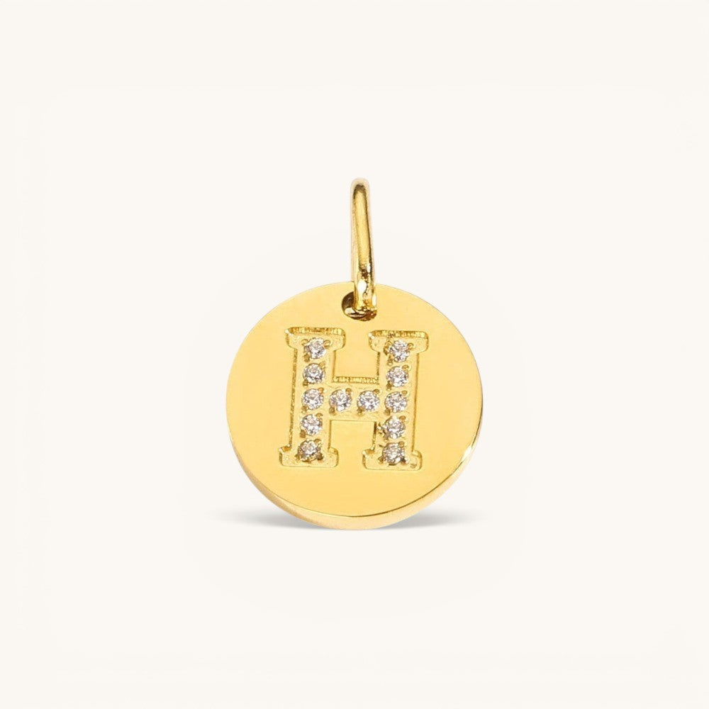 Nadare Co. gold initial H charm with pavé diamond accents on a polished disc.