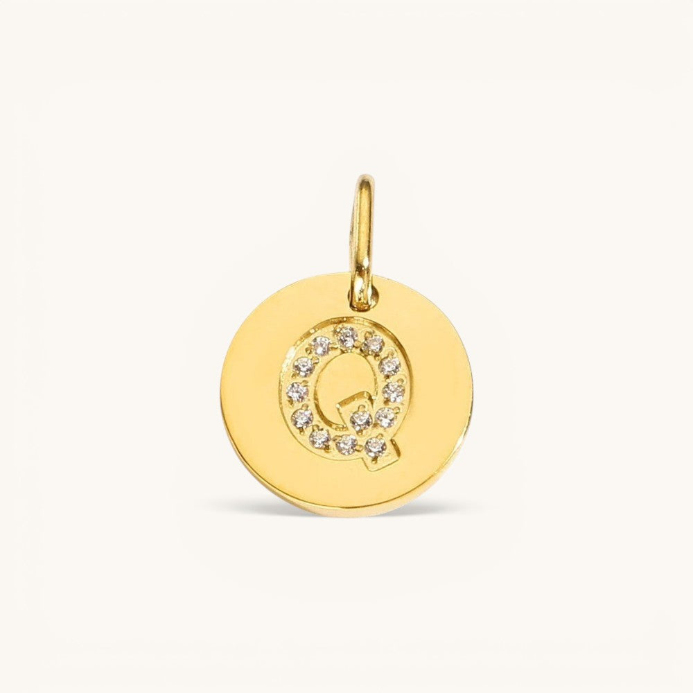 Nadare Co. gold initial Q charm with pavé crystal accents on a polished disc.