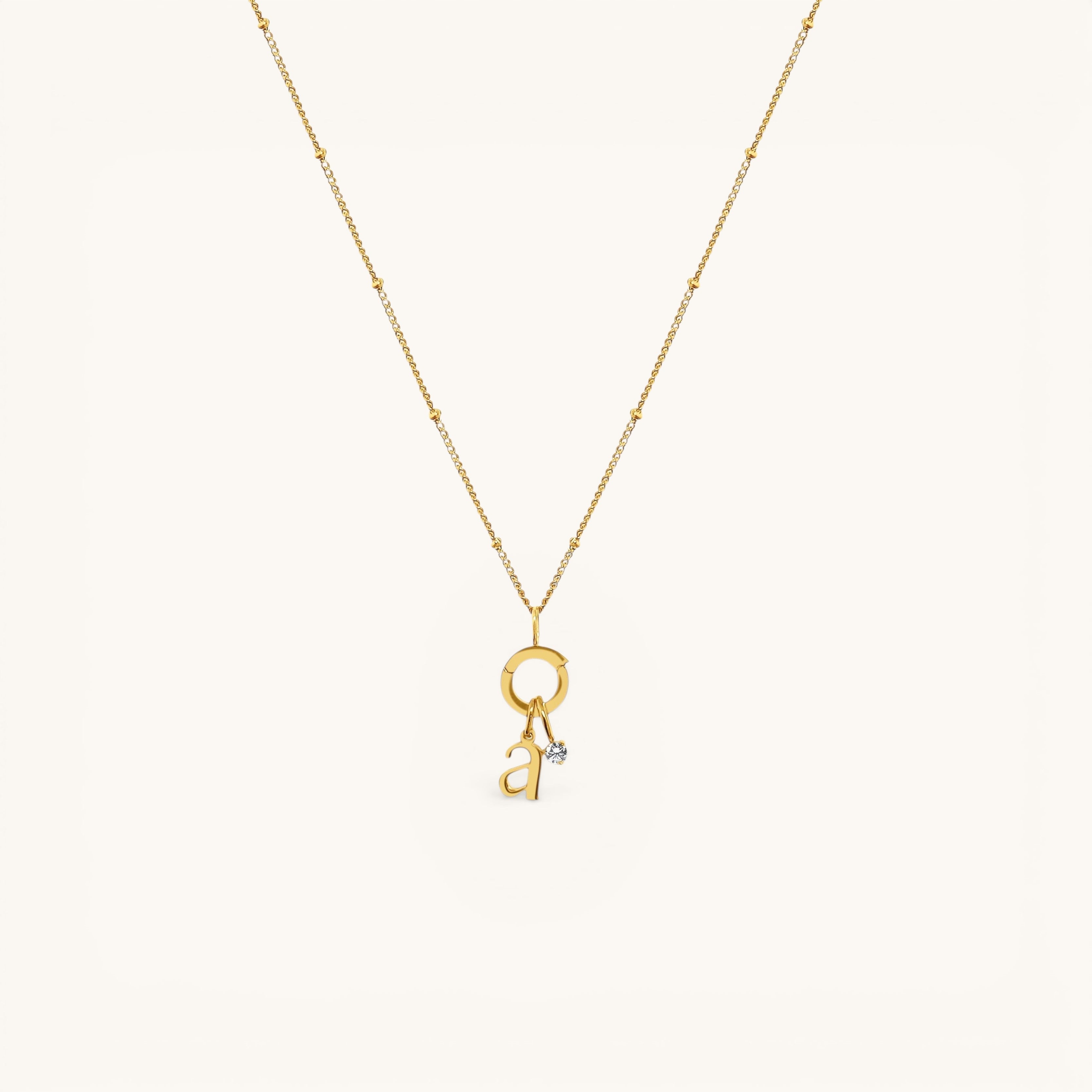 Nadare Co. gold chain necklace featuring a delicate letter charm and a sparkling mini birthstone pendant.