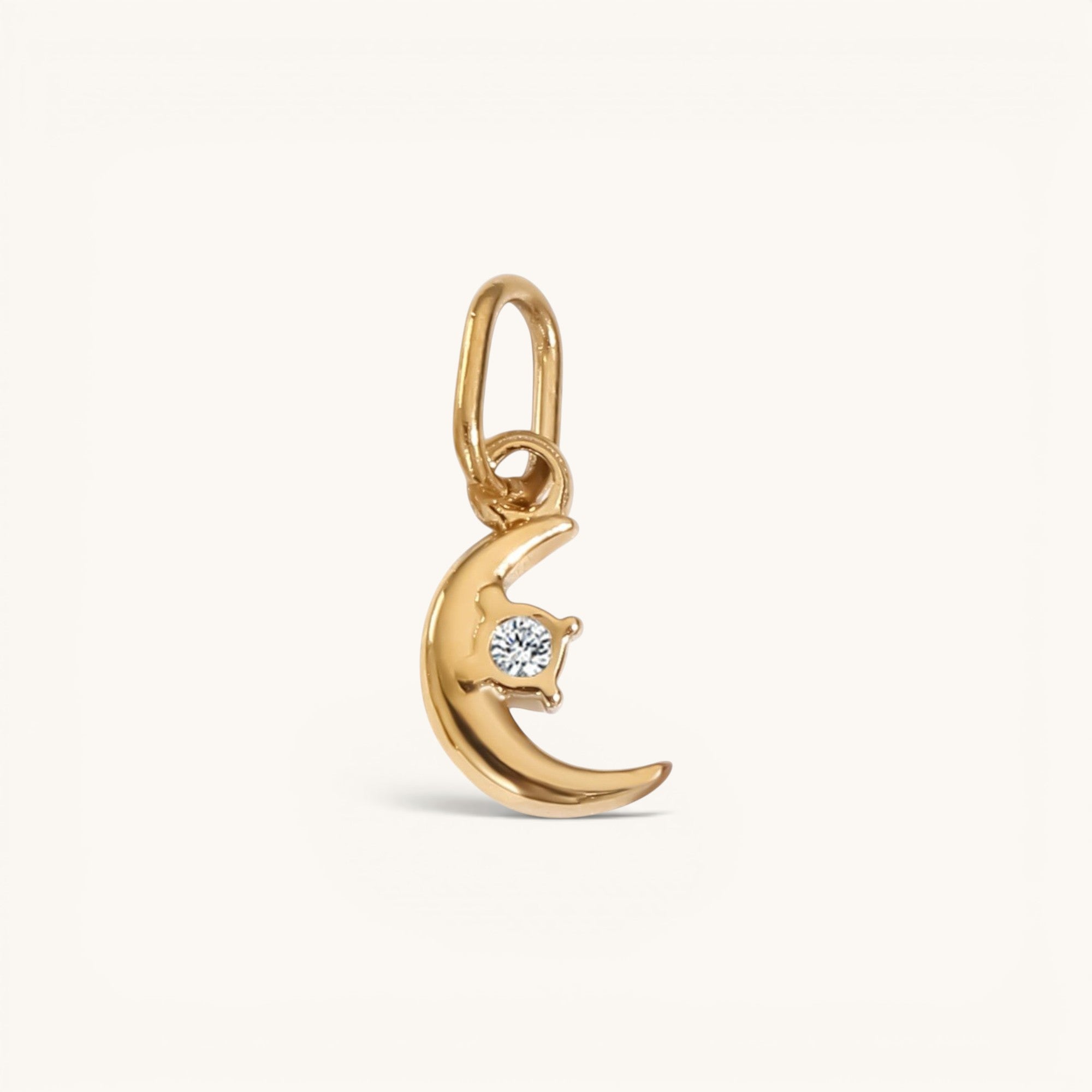 Nadare Co. gold crescent moon charm pendant featuring a small sparkling white diamond accent.