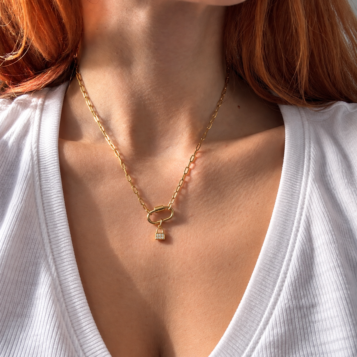 Nadare Co. mini gold padlock charm with cubic zirconia on a delicate chain worn by a woman in a white ribbed top.