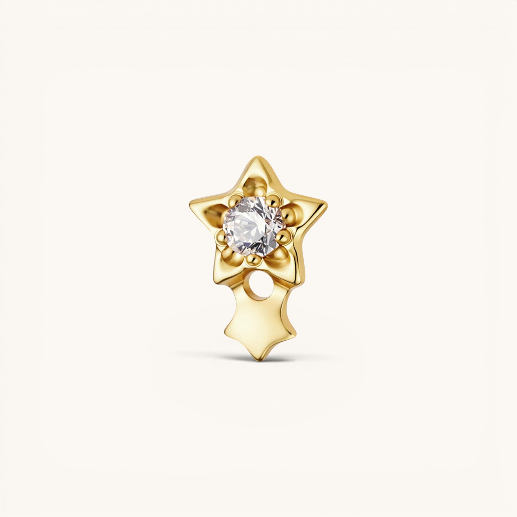 Nadare Co. gold titanium shooting star threadless piercing front with a central cubic zirconia and dangling charm.