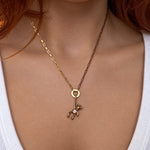 Nadare Co. gold teddy bear charm necklace with cubic zirconia heart on a delicate gold chain worn on a person