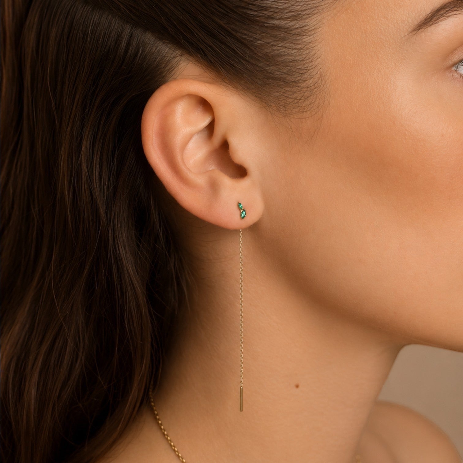 Nadare Co. gold threader earring with green stone detail worn in a model's earlobe