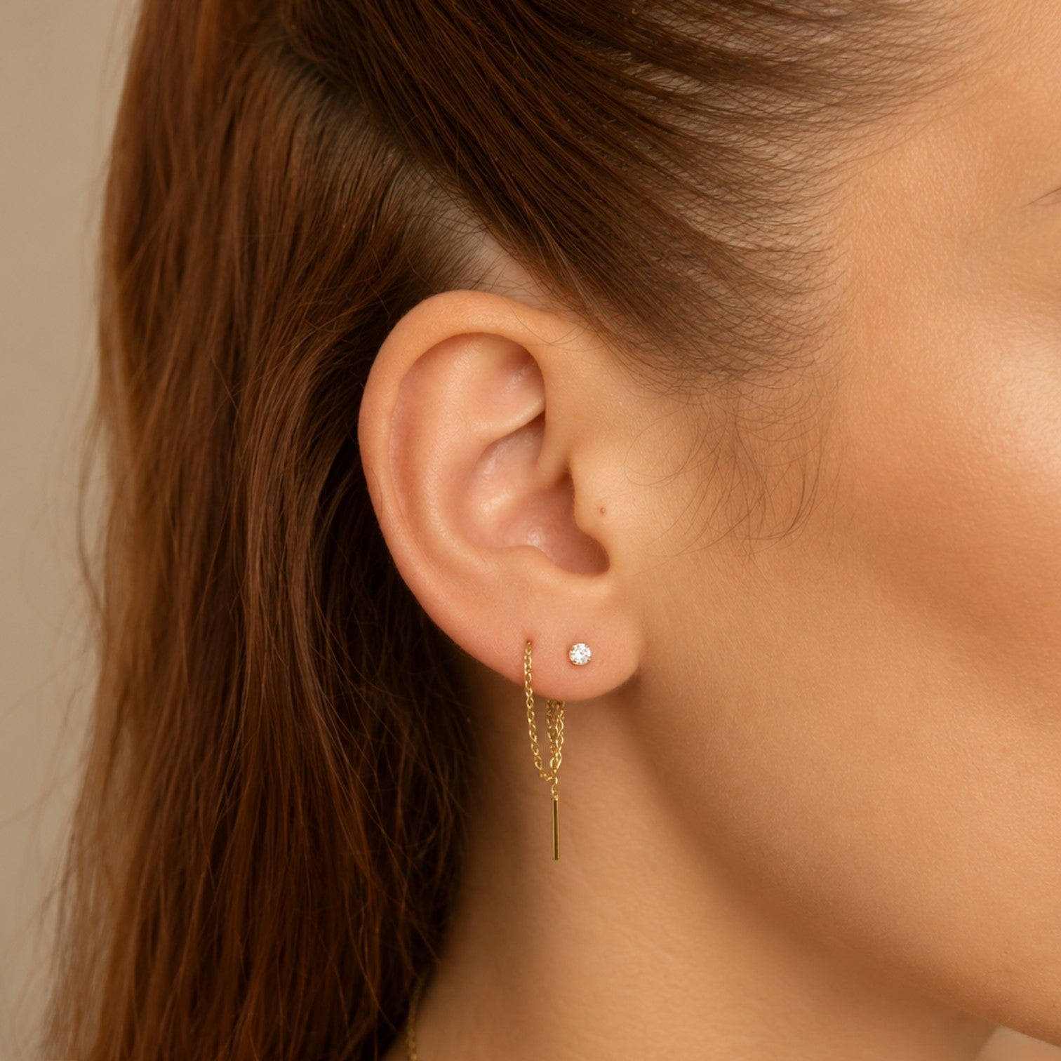 Nadare Co. gold threader earring worn in a pierced ear with a minimalist chain design and a small stud