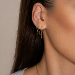 Nadare Co. gold chain threader earrings worn in multiple ear piercings with a small hoop in the tragus