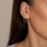 Nadare Co. gold chain threader earrings worn in multiple ear piercings with a small hoop in the tragus