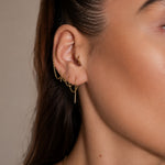 Nadare Co. gold chain threader earrings worn in multiple ear piercings on a woman's ear