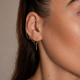 Nadare Co. gold chain threader earrings worn in multiple ear piercings on a woman's ear