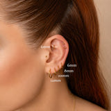 Nadare Co. gold titanium clicker ring worn in a helix piercing on a model with multiple ear piercings