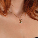 Nadare Co. gold gothic initial necklace with a heart charm and clear birthstone worn on a woman's neck