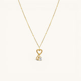 Nadare Co. gold necklace featuring a heart charm, a gothic initial pendant, and a sparkling rectangular birthstone.