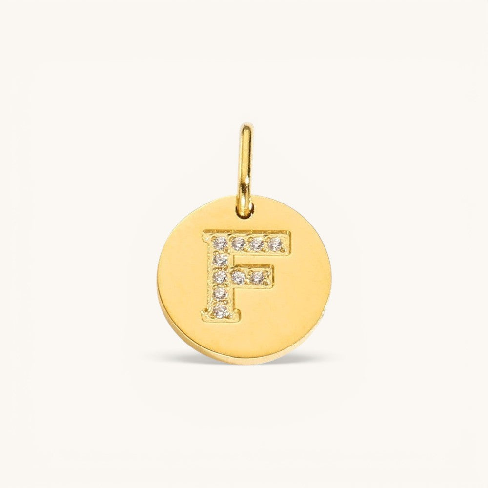 Nadare Co. gold-tone initial F charm with pavé crystal accents on a polished disc.