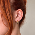 Nadare Co. Lola Hoops in polished gold stainless steel worn on a woman with red hair, showing a classic round design.
