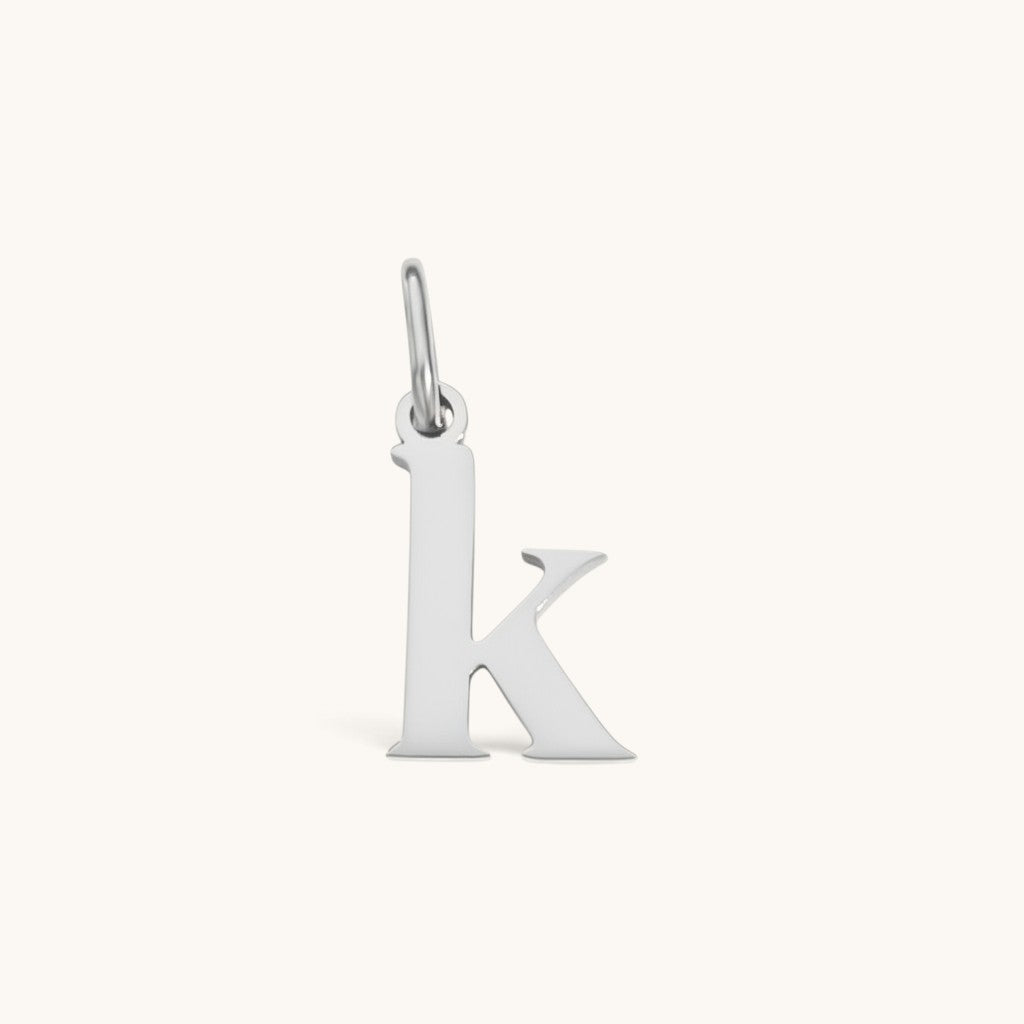 Nadare Co. lowercase letter k charm in silver-tone stainless steel for everyday jewelry layering.