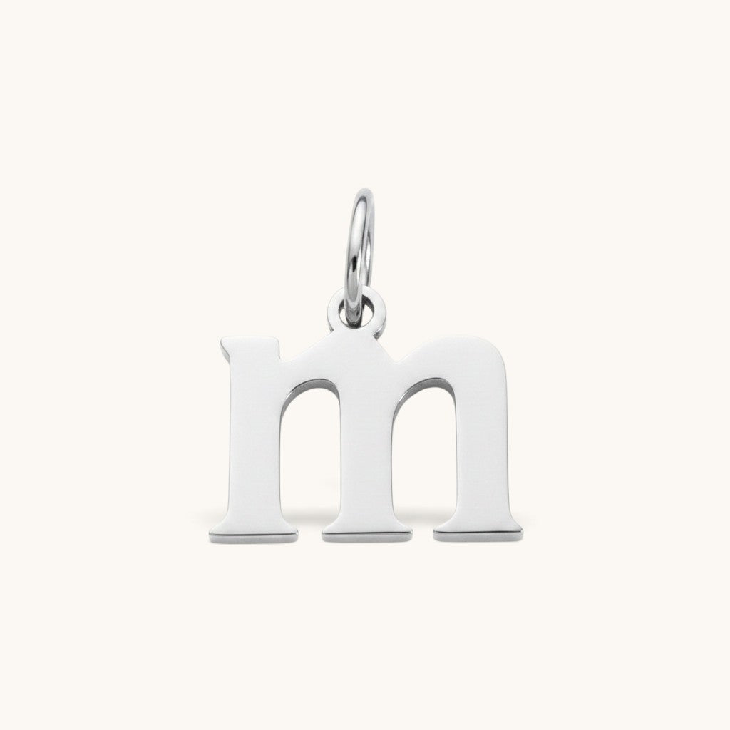 Nadare Co. lowercase letter m charm in polished silver-tone stainless steel for everyday layering.