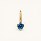 Nadare Co. mini birthstone charm featuring a round-cut blue gemstone set in polished gold on a small hoop.
